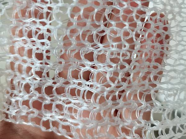 A hand is holding a PP gas-liquid filter knitted mesh of mist eliminator.