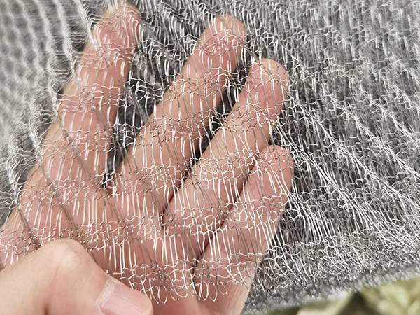 A hand is holding a stainless steel gas-liquid filter knitted mesh of mist eliminator.