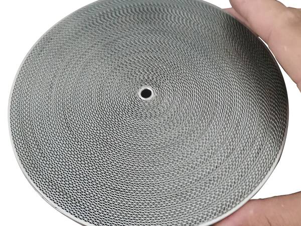 A hand is putting next to a stainless steel corrugated flame arrestor element.